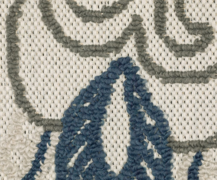 Close-up of the Oriental Weavers Torrey / 072J1 Rug, featuring embroidered blue and gray threads forming abstract motifs on a cream-colored background. The textured stitches create a detailed, raised pattern that accentuates the sophisticated neutral tones of the Torrey Collection.