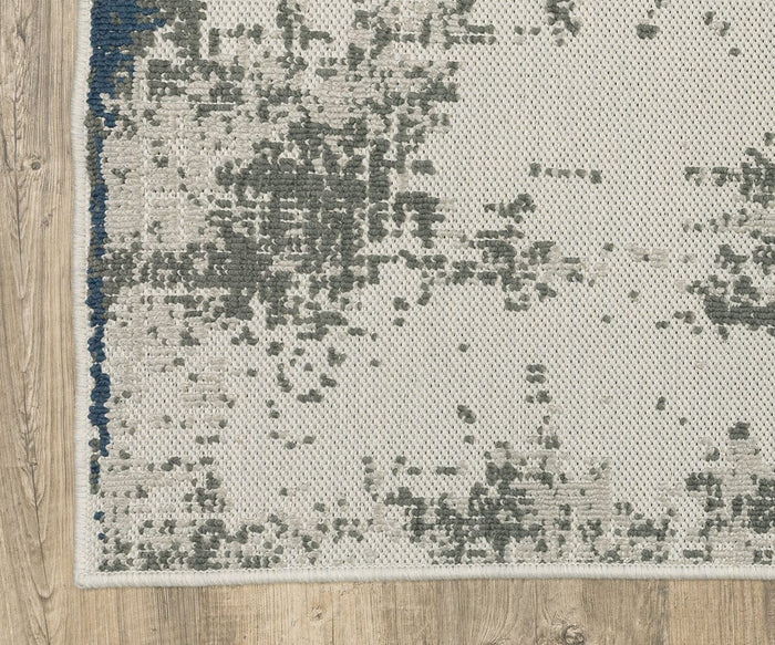 A close-up of the Oriental Weavers Torrey / 140H Rug highlights its abstract grey and blue motifs on a light background, framed by neutral-toned light wood flooring.