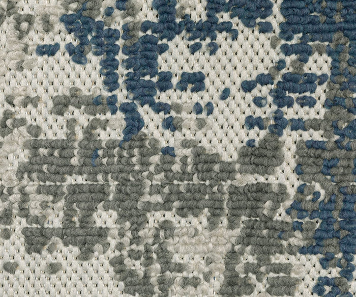 Close-up of the Oriental Weavers Torrey / 140H Rug, showcasing its textured, woven construction with abstract blue and gray motifs set against a light beige background in neutral tones. The looped yarn design creates a soft, raised surface.