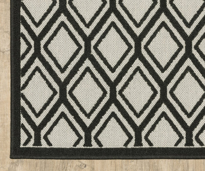 A close-up of the Oriental Weavers Torrey / 4151G Rug showcases its black and white geometric diamond pattern resting on a light wood floor, artfully combining neutral tones with bold abstract motifs.