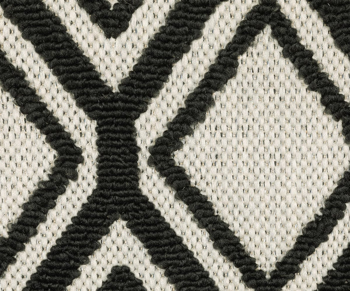 Close-up of the Oriental Weavers Torrey / 4151G Rug, showcasing abstract motifs with bold black geometric diamond and X patterns on a cream background. The texture features raised, thick black lines over a flat, tightly woven surface, highlighting the interplay of neutral tones.