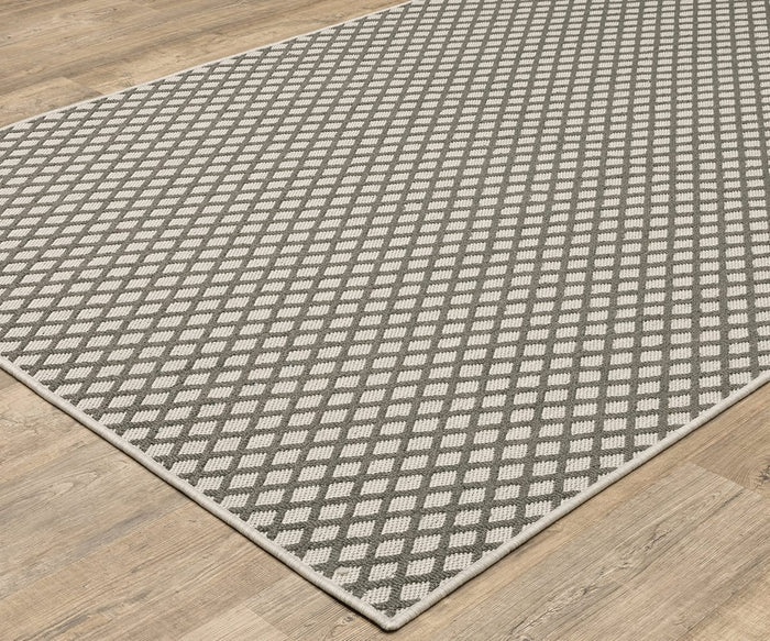 A close-up of the Oriental Weavers Torrey / 501H1 Rug, featuring a white diamond pattern on a gray background and placed on a light wood floor, highlights its neutral tones and understated elegance.