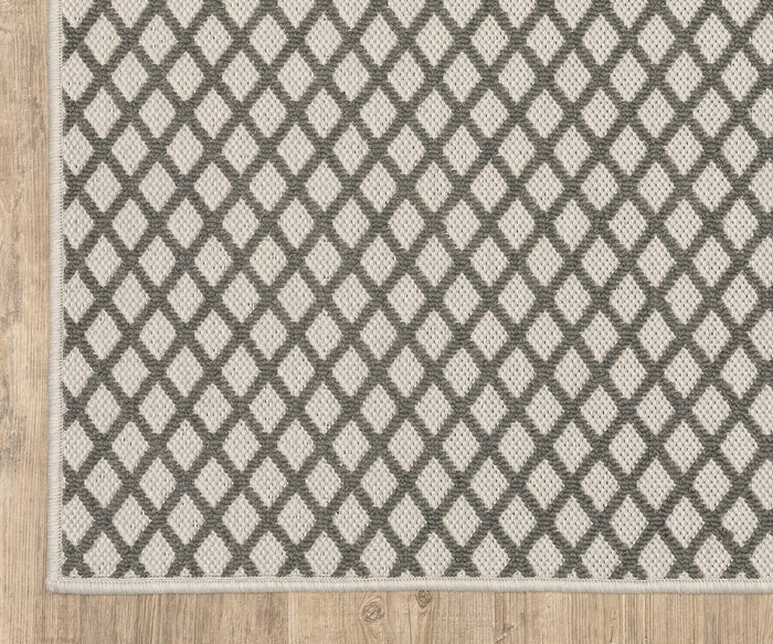A corner of the Oriental Weavers Torrey / 501H1 Rug featuring a repeating diamond pattern in neutral gray and white tones, displayed on a light wood floor.