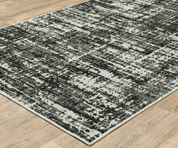 The Oriental Weavers Torrey / 531W Rug, featuring black, gray, and white abstract pixelated motifs in neutral tones, lies on a light wooden floor.