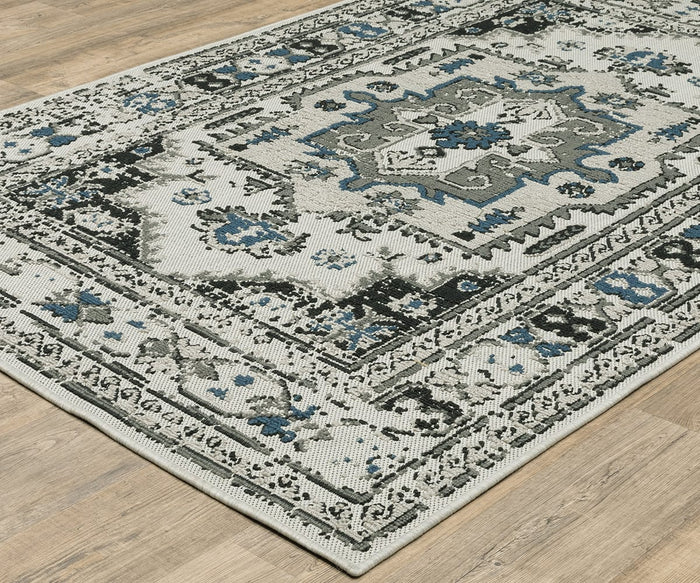 The Oriental Weavers Torrey / 5561H Rug is a rectangular area rug featuring a vintage-style geometric pattern in gray, black, and blue tones, with layered texture and subtle abstract motifs that look beautiful placed on a light wood floor.