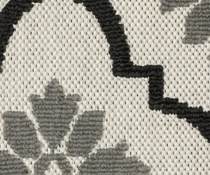 Close-up of the Oriental Weavers Torrey / 5562E Rug, featuring a woven fabric with abstract motifs and a geometric and floral pattern in black and gray on a cream background, highlighting the dynamic texture of interlaced threads characteristic of flatwoven rugs.
