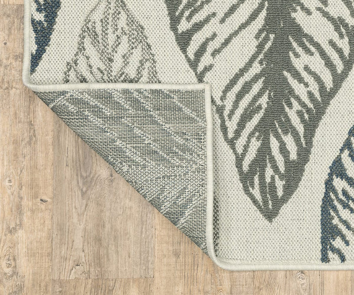 A corner of the Oriental Weavers Torrey / 5570Y Rug, adorned with intricate leaf patterns, is folded over to showcase its underside and layered texture as it rests elegantly on a light wood floor.