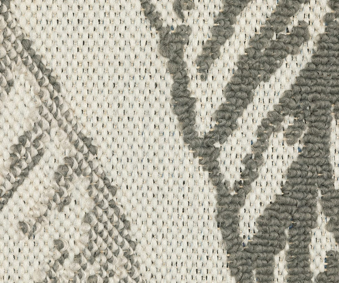 Close-up of the Oriental Weavers Torrey / 5570Y Rug, showcasing a textured, off-white woven background with gray, raised yarn forming abstract motifs in an organic pattern. The visible weave and fibers highlight the rug’s intricate structure and layered texture.