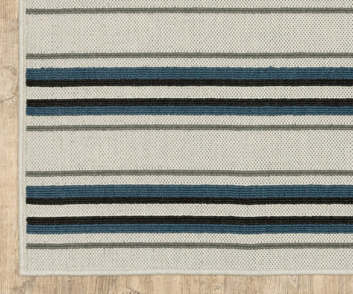 A portion of the Oriental Weavers Torrey / 5571Y Rug, showcasing horizontal stripes in gray, blue, and black with subtle abstract motifs on a beige background, is placed on a light wood floor.