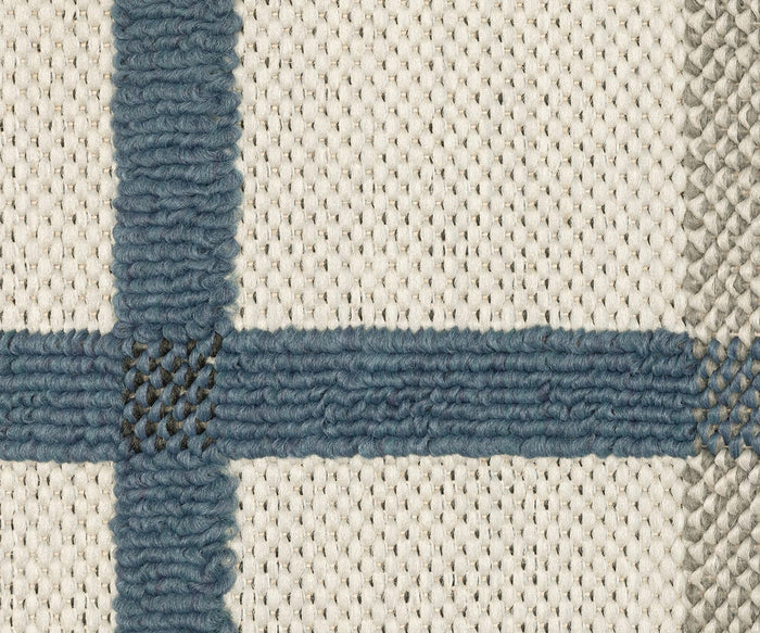 Close-up of the Oriental Weavers Torrey / 7150H Rug reveals a woven fabric with a cream background, accented by intersecting blue and gray stripes that create a grid pattern. Reminiscent of a classic flatwoven rug, the texture of the yarn and weave is clearly visible, emphasizing the subtle elegance of its neutral tones.