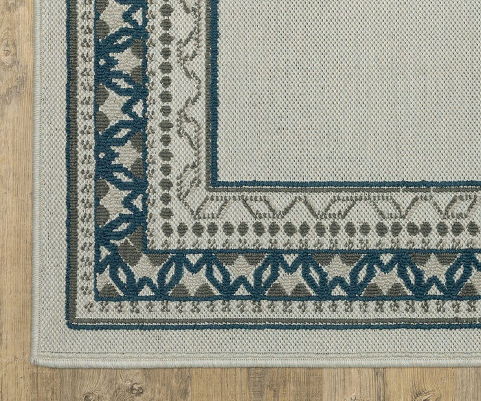 Close-up of the Oriental Weavers Torrey / 8020W Rug, a rectangular woven piece from the Torrey Collection, showcasing a geometric and floral border pattern in blue and gray tones with dynamic texture throughout. The visible corner highlights its intricate abstract motifs and is placed on a light wood floor. Only the rug’s corner is shown in the image.