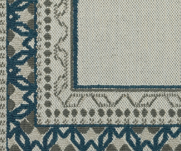 Close-up of a woven rug corner from the Oriental Weavers Torrey / 8020W Rug, showcasing teal, gray, and cream geometric patterns with dynamic texture and intricate decorative borders.