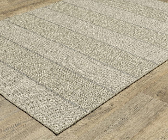 The Oriental Weavers Tortuga / TR01A Rug, a beige woven area rug with subtle horizontal stripes and a textured pattern in neutral tones, is placed on a light wood floor. Made from easy-care polypropylene, it perfectly complements the flooring beneath it.