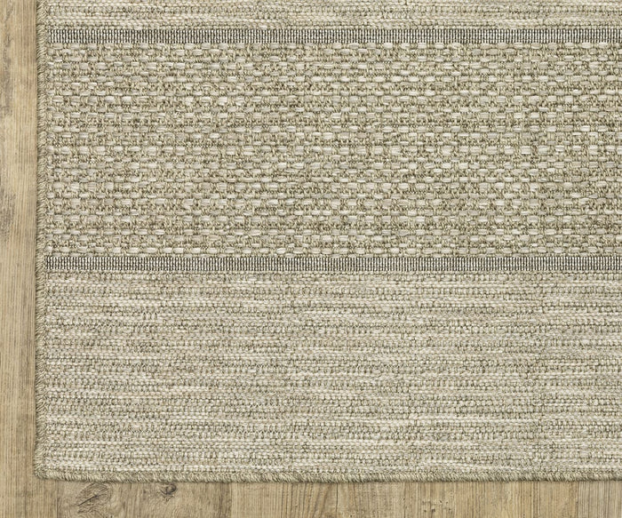 An Oriental Weavers Tortuga / TR01A Rug in beige, featuring a textured pattern with two wide horizontal stripes, is displayed on a light wood floor. The easy-care polypropylene rug’s weave and finished edge are prominently shown in the image.