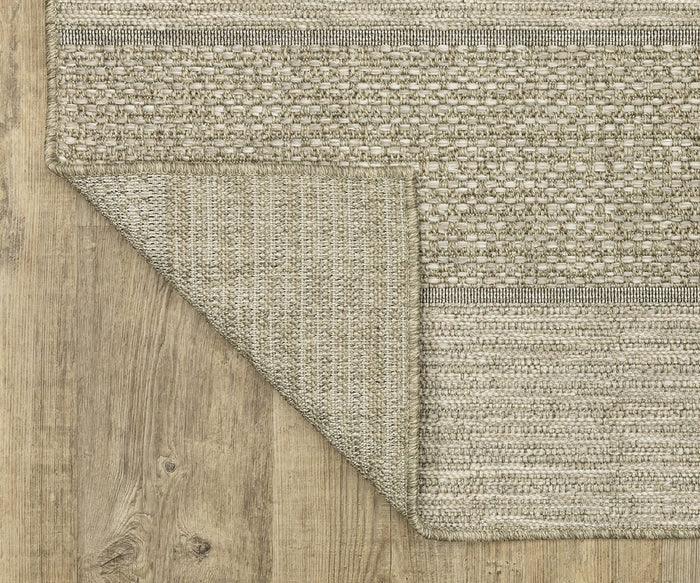 The Oriental Weavers Tortuga / TR01A Rug in beige features a textured weave, beautifully displayed with one corner folded over to showcase the detailing on both sides. Crafted from easy-care polypropylene, this rug rests atop a light wooden floor with visible grain patterns, bringing warmth and style to your space.