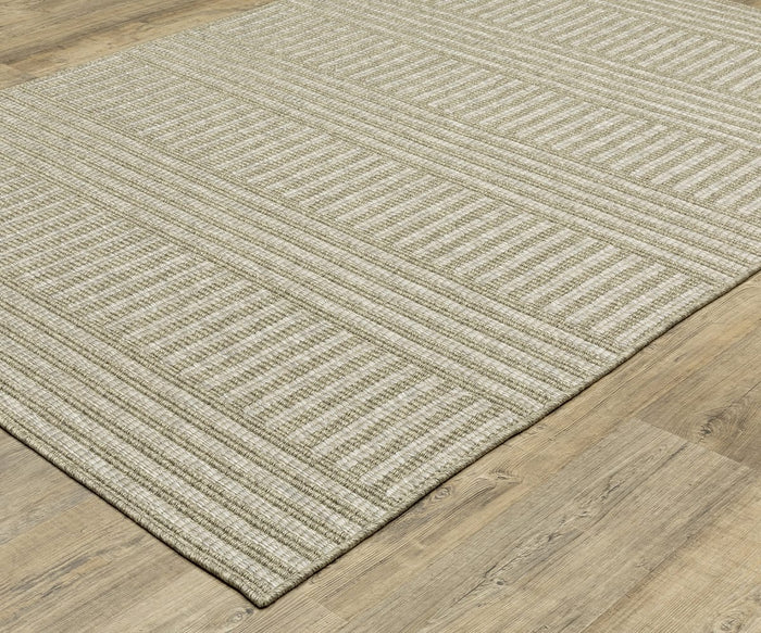 The Oriental Weavers Tortuga / TR02A Rug, featuring a beige hue with a subtle striped and checkered pattern, rests on a light wood floor. This easy-care rug from the Tortuga Collection boasts a textured, woven look and clean, finished edges.