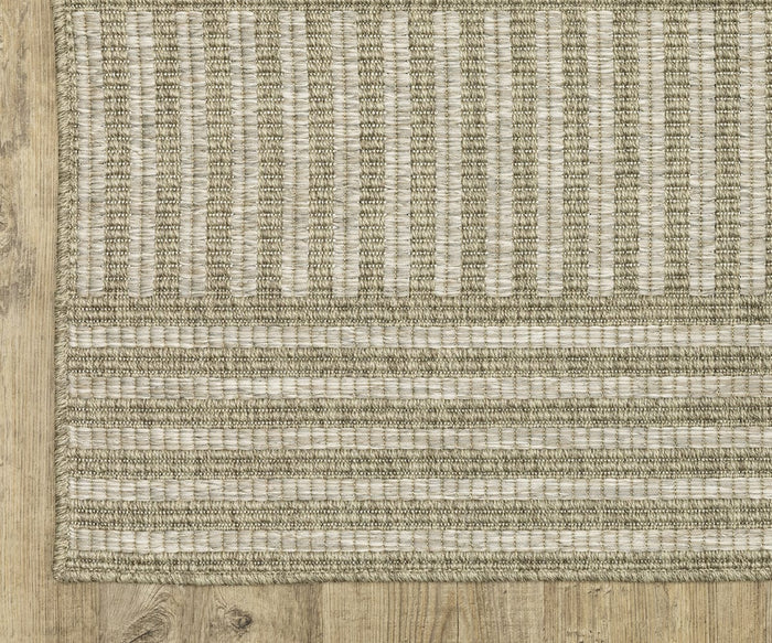 A close-up of the Oriental Weavers Tortuga / TR02A Rug in beige and cream, featuring woven vertical and horizontal stripe patterns, placed on a light wood floor. This easy-care rug from the Tortuga Collection offers a blend of durability and understated style.