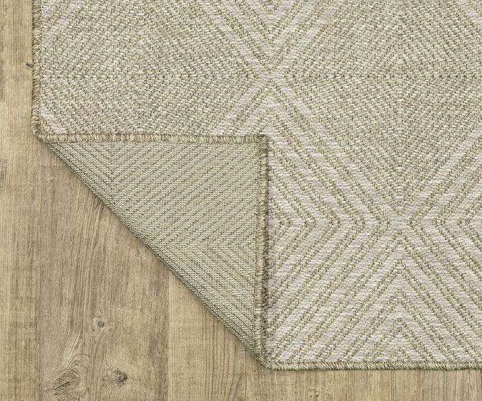 An Oriental Weavers Tortuga / TR05A Rug, featuring a beige woven design and geometric pattern, lies on a wooden floor. One corner of this easy-care polypropylene rug is folded over to reveal the texture and stitching on the underside.