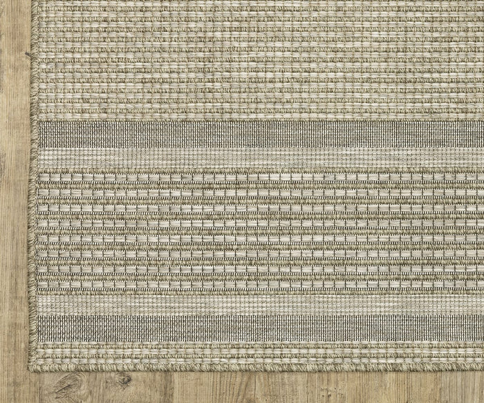 A close-up of the Oriental Weavers Tortuga / TR07A Rug showcases its woven beige and gray design with horizontal stripe patterns, elegantly placed on a light wooden floor. Crafted from easy-care polypropylene, this rug is both stylish and practical for everyday living.