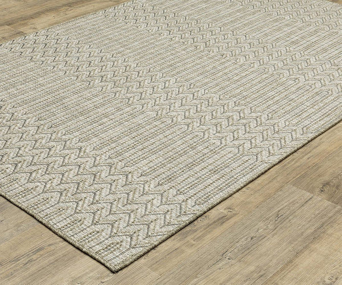 The Oriental Weavers Tortuga / TR09A Rug is a beige woven area rug from the Tortuga Collection, featuring geometric zigzag and chevron patterns. Crafted from durable polypropylene for easy care, this stylish rug is shown placed on a light wood floor.