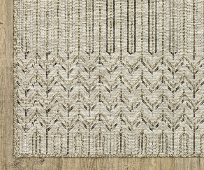 The Oriental Weavers Tortuga / TR09A Rug, made from beige woven polypropylene, showcases a bold zigzag chevron pattern on the bottom half and vertical lines on the top, elegantly laid on a light wooden floor. This easy-care rug perfectly blends style and practicality for contemporary living spaces.