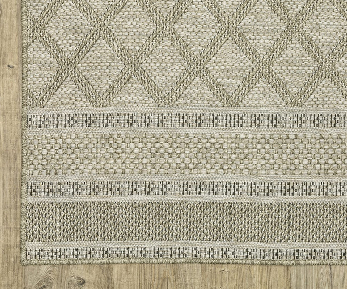The Oriental Weavers Tortuga / TR10A Rug, a beige and gray power-loomed piece featuring diamond and horizontal stripe patterns, is placed on a light wood floor.