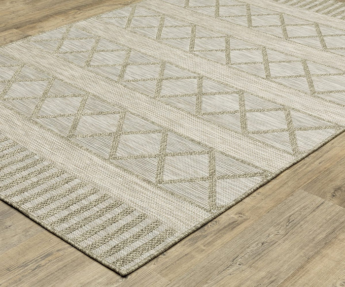 The Oriental Weavers Tortuga / TR11A Rug, with its beige and light green geometric diamond and striped pattern, sits on a light wood floor. This easy-care polypropylene rug from the Tortuga Collection blends modern style with durability for everyday living.
