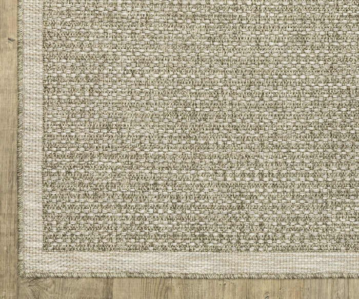 A close-up of the Oriental Weavers Tortuga / TR12A Rug showcases its beige woven texture and subtle pattern, bordered by a simple trim, resting on a light wood floor. Power-loomed from durable polypropylene, this easy-care rug is designed for everyday convenience.