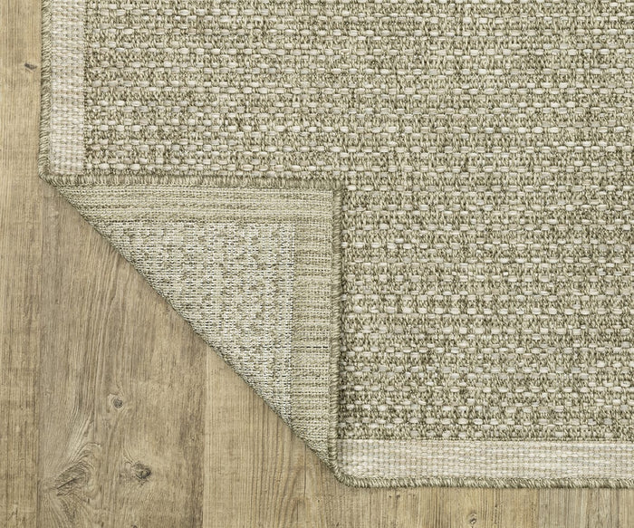A close-up of the Oriental Weavers Tortuga / TR12A Rug in beige, displayed on a wooden floor with one corner folded over to reveal its easy-care underside and textured weave.