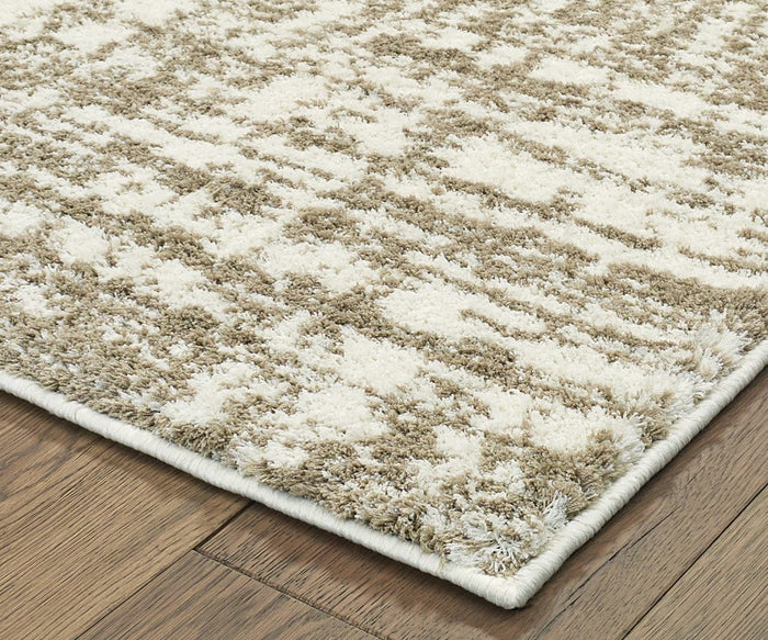 An Oriental Weavers Verona / 1803J Rug, crafted from soft polyester microfiber and featuring a beige and cream geometric pattern, sits on a medium-toned wooden floor. The rug has a textured surface and neatly finished edges.