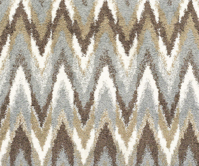 A close-up of the Oriental Weavers Verona / 4D Rug showcases its textured polyester microfiber surface with a repeating zigzag chevron pattern in beige, brown, gray, and white hues. The rug offers a soft, plush appearance and a neutral palette that complements any space.