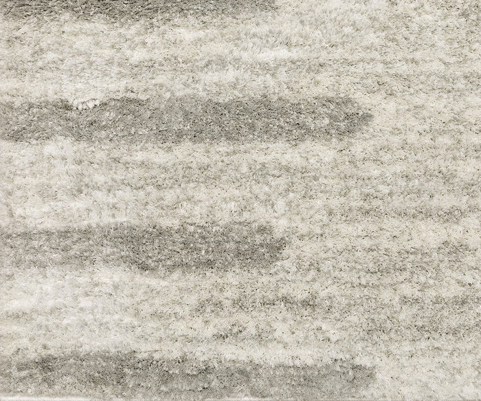 A close-up of the Oriental Weavers Verona / 5605HG Rug showcases its textured, plush surface with a wavy pattern in multiple shades of gray and off-white. Made from soft polyester microfiber, this rug features a neutral palette and an invitingly soft, fluffy appearance.