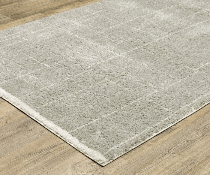 The Oriental Weavers Verona / 752G Rug, featuring a light gray hue and subtle geometric motifs, lies on a wooden floor. Crafted from soft polyester microfiber with clean edges, this rug seamlessly complements the surrounding space while bringing understated elegance through its gentle patterns.