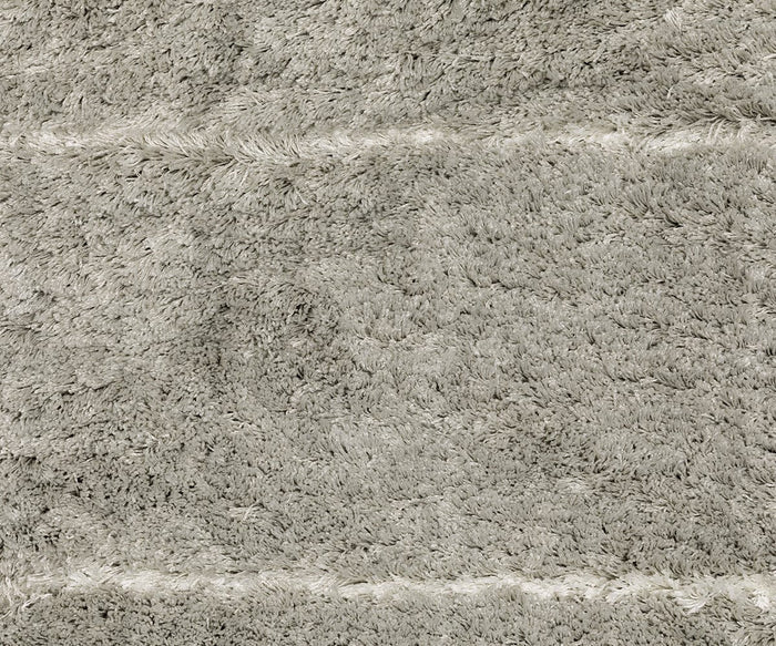 Close-up of the Oriental Weavers Verona / 752G Rug, a light gray, plush shaggy carpet from the Verona Collection. It features subtle horizontal lines and textured polyester microfiber fibers for a soft and cozy feel. Delicate geometric motifs enhance the design with understated elegance.