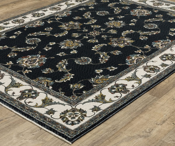 The Oriental Weavers Vivian / VI01B Rug, featuring a black background with intricate floral and vine patterns and a light beige border, brings timeless elegance to your space when placed on a light wood floor.