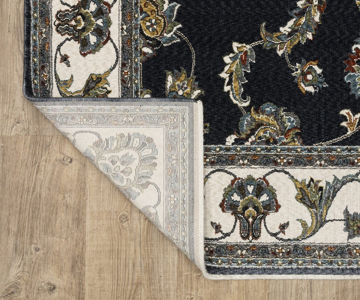 The Oriental Weavers Vivian / VI01B Rug, featuring a Persian-inspired floral pattern with a dark background and ornate border, is displayed on a wooden floor. One corner is turned over to reveal the lighter, decorative underside of this elegant traditional area rug.