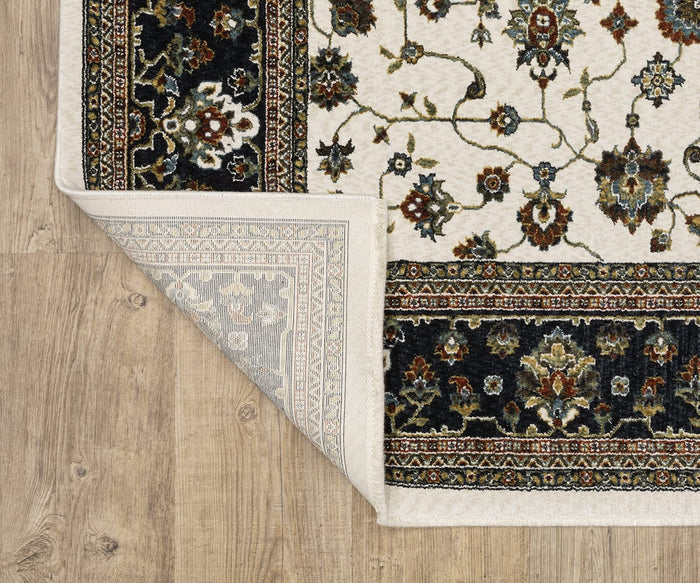 Corner of the Oriental Weavers Vivian / VI02B Rug, a decorative piece featuring intricate Persian-inspired floral patterns in a traditional palette of black, cream, and brown. The rug is shown partially flipped over on a light wooden floor, displaying its woven underside crafted from soft microfiber polyester.