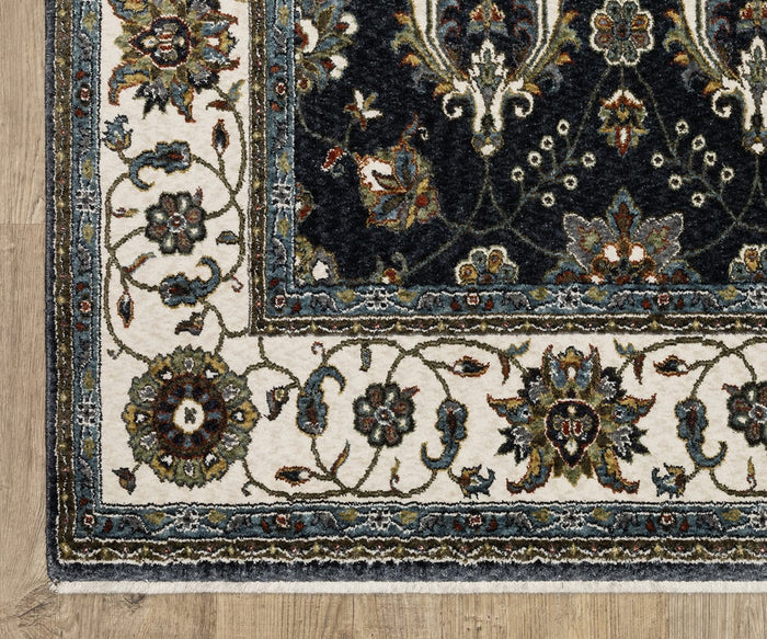 A close-up of the corner of the Oriental Weavers Vivian / VI03A Rug, featuring a floral pattern in cream, black, blue, and green tones, woven from soft microfiber polyester and displayed on a light wooden floor.