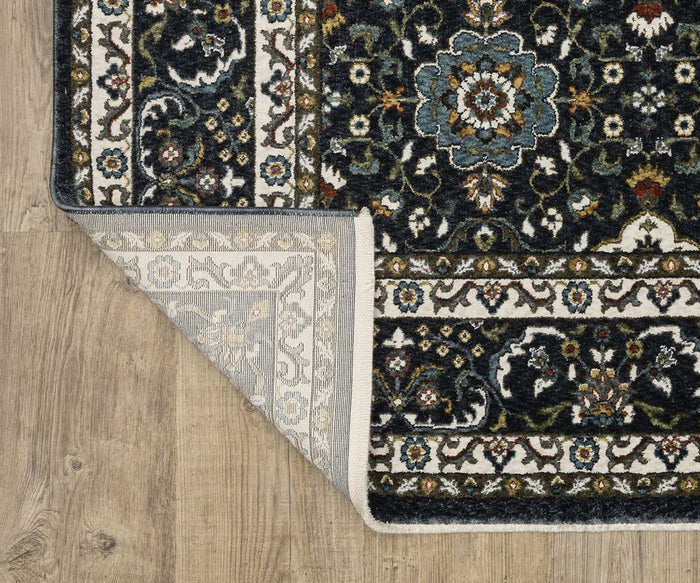 A corner of the Oriental Weavers Vivian / VI04C Rug is flipped over, revealing the underside. Crafted from soft microfiber polyester, this rug features dark and light floral designs reminiscent of Persian-inspired rugs and lies on a wooden floor.