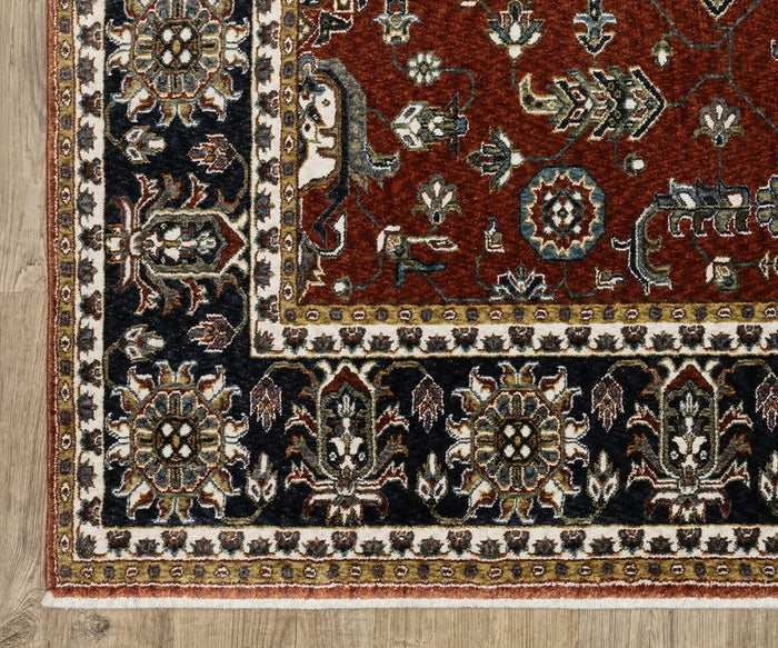 A corner of the Oriental Weavers Vivian / VI05X Rug, showcasing its intricate floral designs in red, black, white, and green hues, lies atop a light wood floor. This Persian-inspired rug features a traditional color palette along its border with repeating floral motifs and geometric shapes that enhance its timeless appeal.