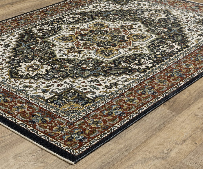 The Oriental Weavers Vivian / VI06C Rug is a Persian-inspired area rug featuring an intricate floral and geometric pattern in shades of black, cream, gold, and burgundy. This ornate rug displays a detailed central medallion and a decorative border, shown here on a light wood floor.