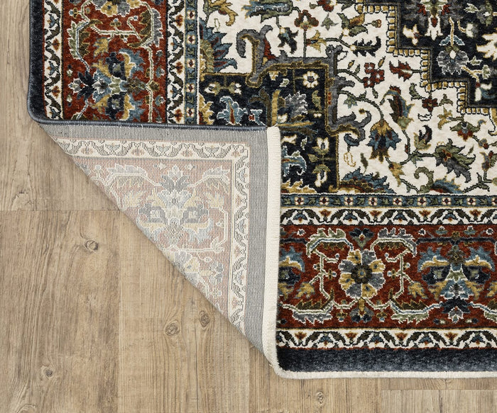 A corner of the Oriental Weavers Vivian / VI06C Rug with traditional floral and geometric motifs is folded over, revealing the underside on a wooden floor. This Persian-inspired area rug features rich shades of red, blue, black, and cream that bring timeless charm to any space.