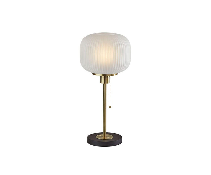 The Patina Table Lamp features a round, fluted pattern frosted glass lampshade, a brass stem, a black circular base, and a hanging pull chain switch, shown against a plain white background.