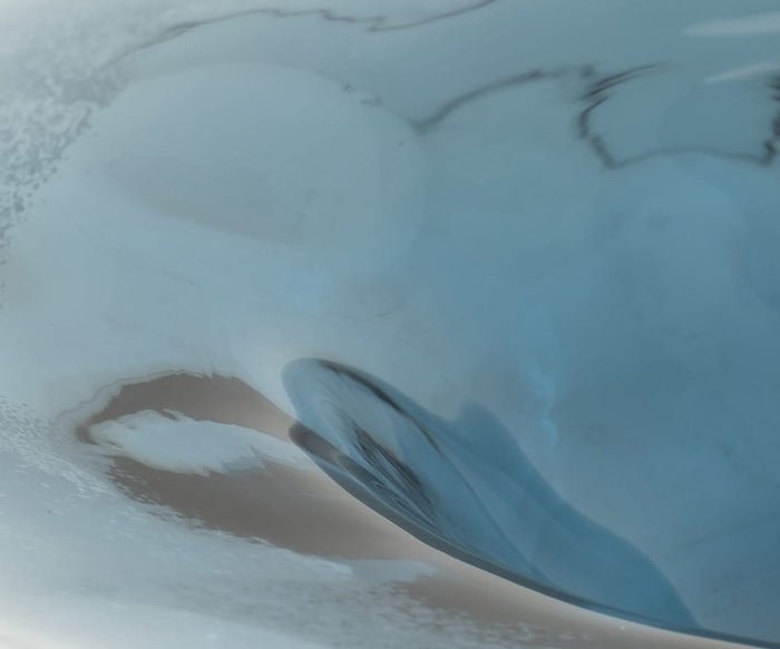 Abstract image featuring soft swirls of blue and white, creating a fluid, watery appearance with smooth transitions between light and dark areas—evoking the Polar Frost Bowl, a stunning decorative piece meticulously crafted from hand-finished glass.