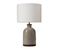 The Polished Terracotta Lamp features a polished grey terracotta base with a glossy finish and a wide, cylindrical fabric lampshade, photographed against a plain white background.