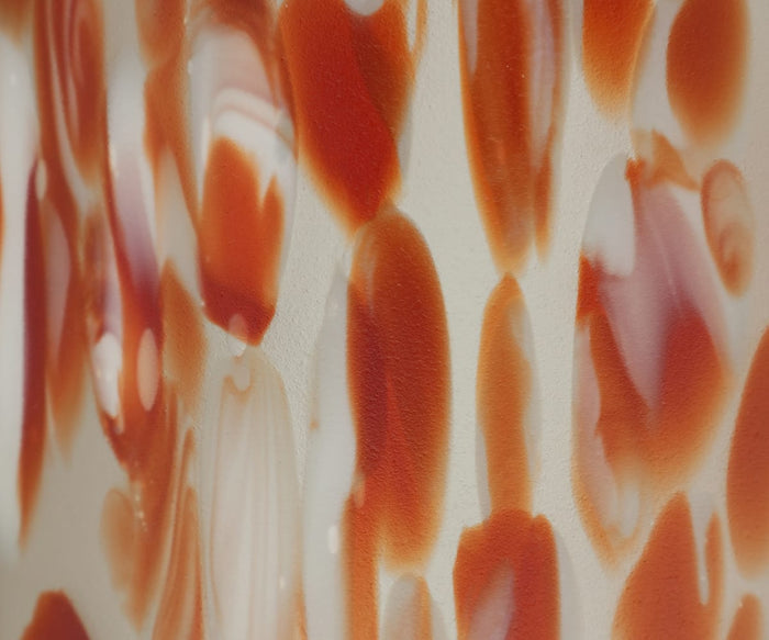 A close-up of the Poppy Frost Vase reveals abstract red and white patterns, featuring irregular oval and streak shapes on a smooth surface reminiscent of hand-finished glass.