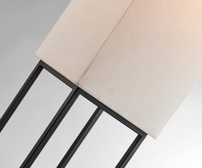 A close-up of the Quinlan Floor Lamp highlights its modern aesthetic with a rectangular beige fabric shade and sleek black metal frame, photographed from an angle against a light gray background. Designed for outdoor use, this weather-resistant, cordless floor lamp seamlessly combines style and practicality for your outdoor living area.