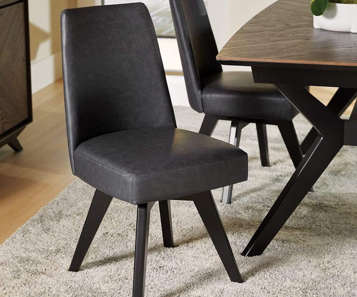 A modern Raynor Swivel Dining Chair in black upholstery, featuring angled legs, sits atop a light-colored rug beside a wooden dining table. Another matching Raynor chair and part of the table are visible in the background.
