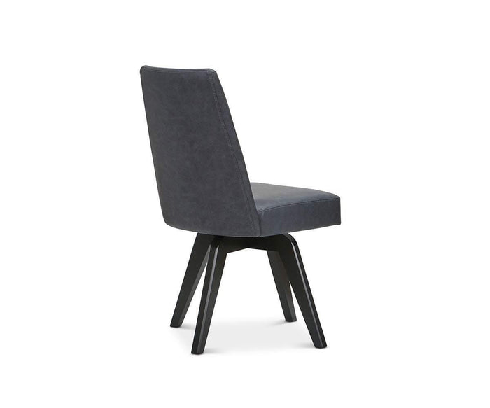 Introducing the Raynor Swivel Dining Chair—a modern upholstered dining chair featuring a dark grey seat and backrest, elegantly angled to showcase its contemporary design. Supported by four black wooden legs set at an angle, this versatile piece is displayed against a plain white background. Perfect as a swivel dining chair, the Raynor is designed to elevate any modern dining space.