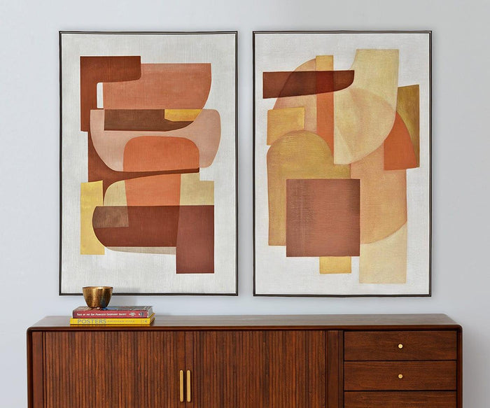 A Retro Sunset I Oil Painting with warm tones of brown, rust, and yellow hangs above a wooden cabinet with gold handles. On top of the cabinet sit two books and a small gold cup, creating a mid-century inspired look.